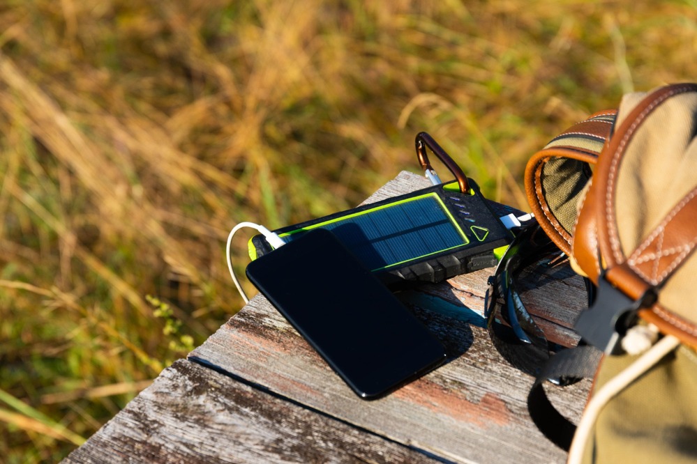 solar-energy-battery-device-power-bank-telephone-wooden-table-with-backpack-solar-charge-your-smartphone-selective-focus.jpg